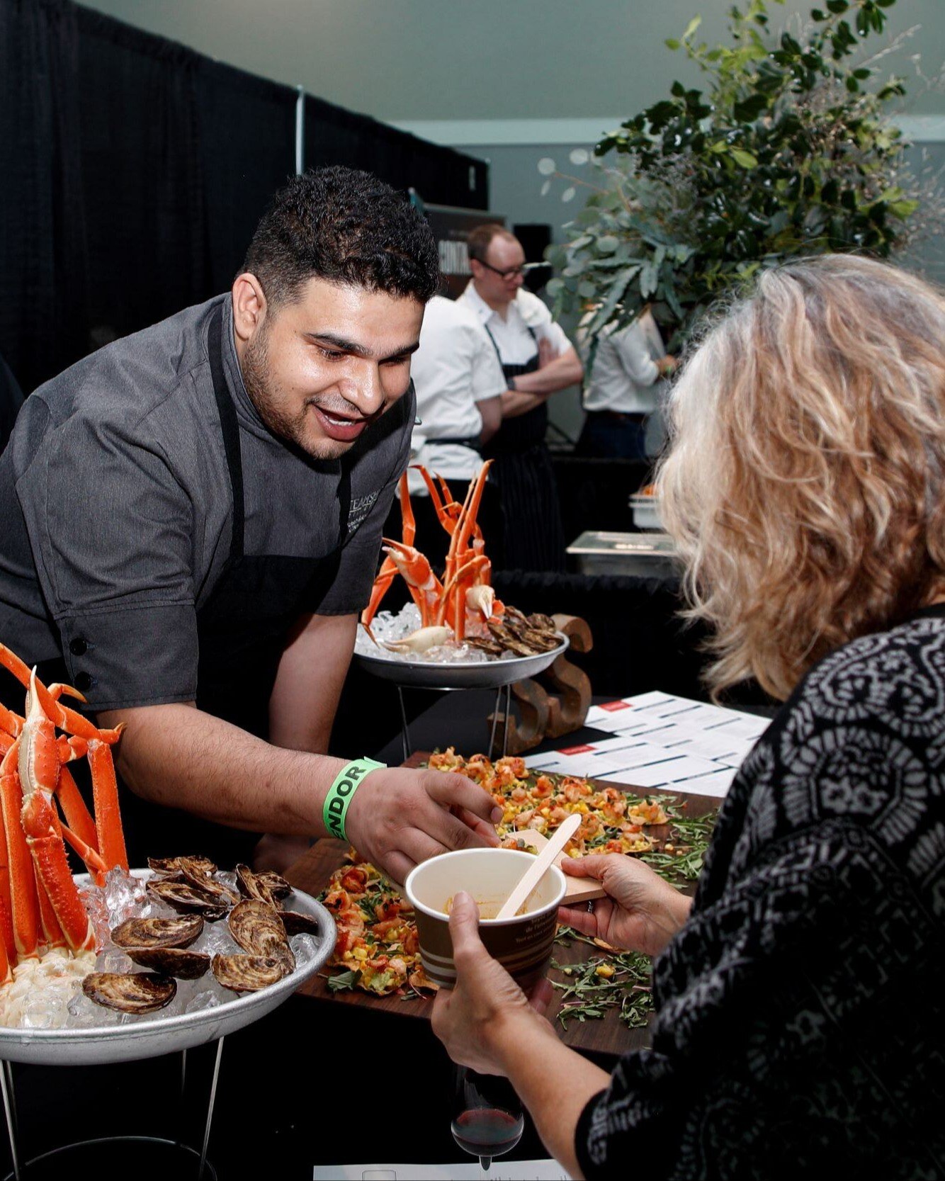 chef handing women a small bite of food at a foodie festival