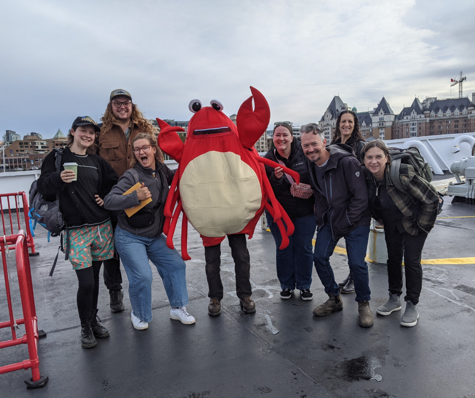 team group of people standing next to a crab mascot